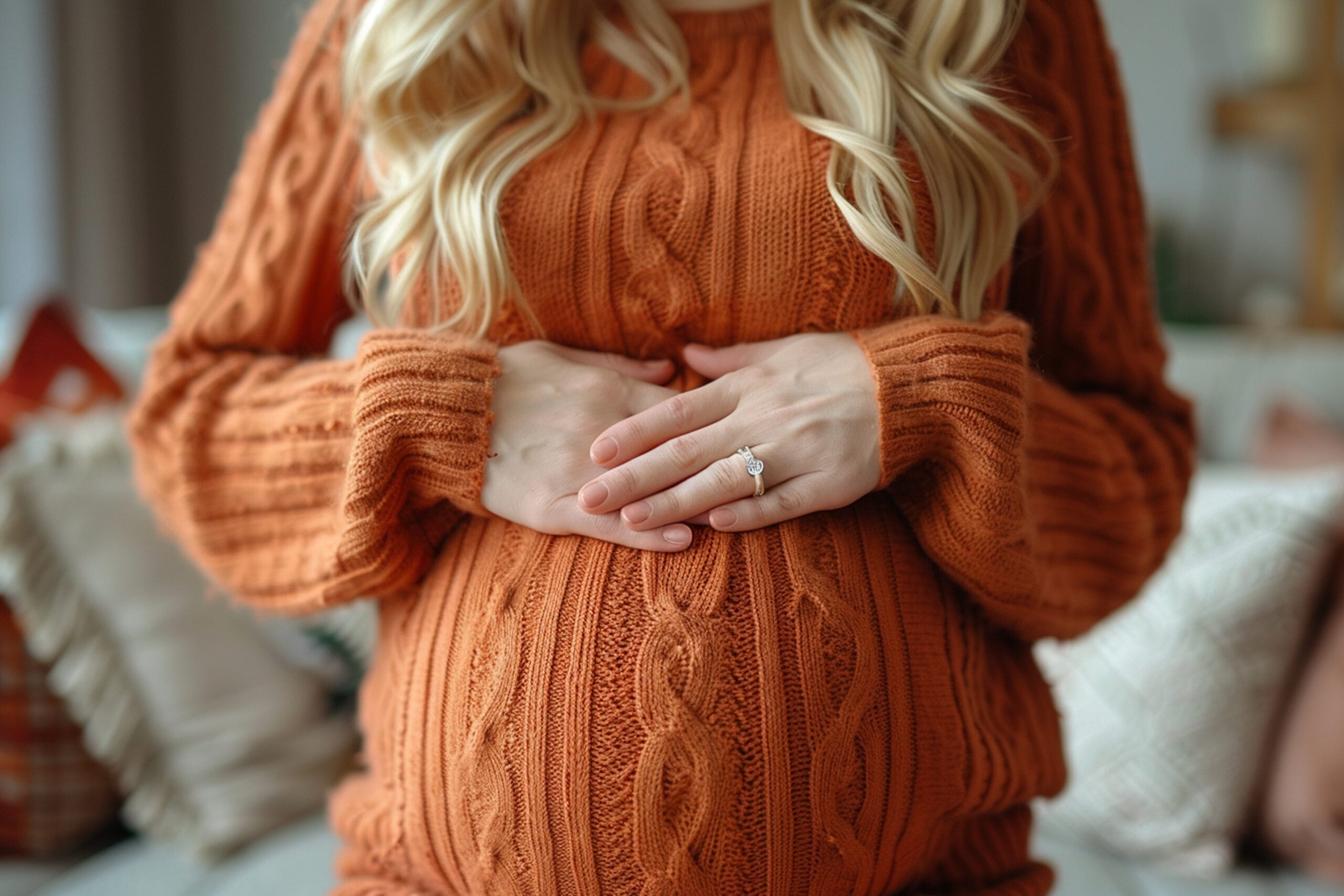 Pregnant woman in orange sweater holding belly showing prenatal care Campbell